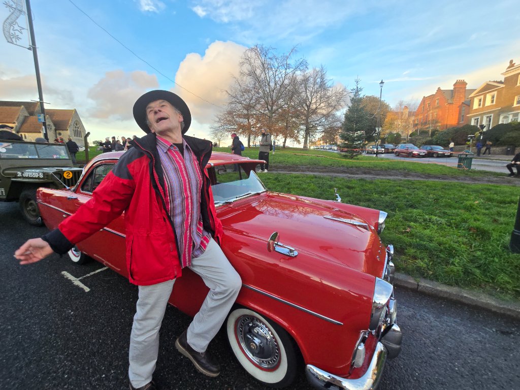 Man in red jacket by a vintage red car at a Blackheath community event