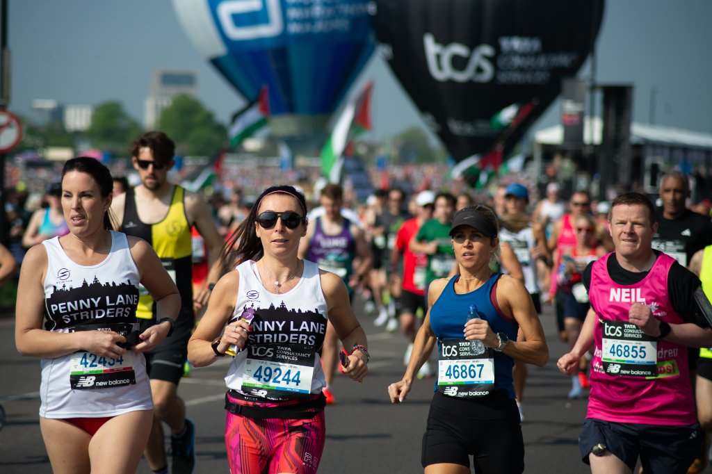 Runners streaming down a long tree-lined hill