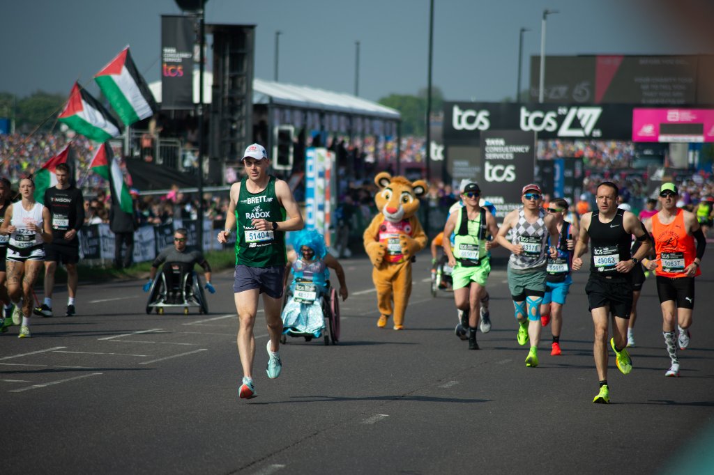 Priest holding a holy water bucket as runners pass